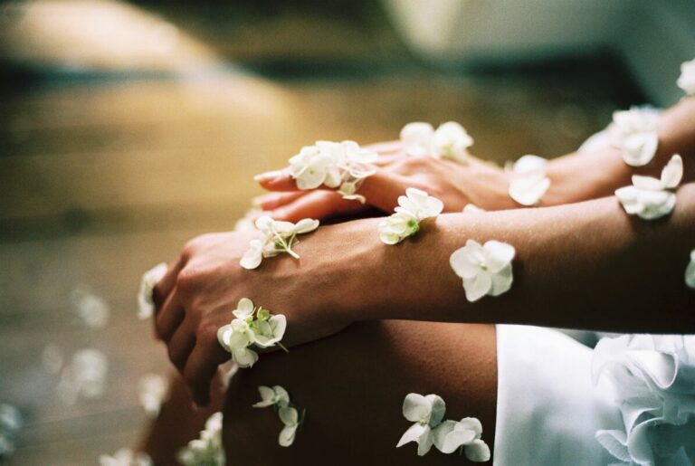 white flowers laid across woman's hands and arm on bare skin for summer skin health blog post roncys apothecary toronto